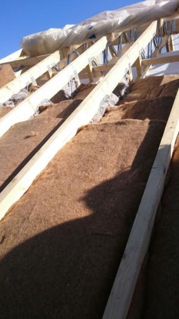 Overlapping lengths of Jute fitted between rafters on a roof.