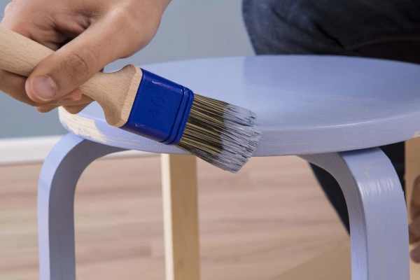A stool being painted blue using Auro natural paint