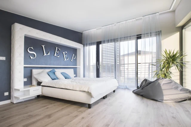 A bedroom with blue walls ventilated by Inventer decentralised ventilation