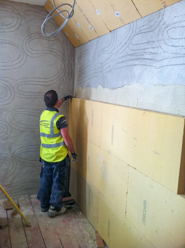 Gutex Thermoroom boards being tapped to ensure the boards are firmly adhered onto the wall.