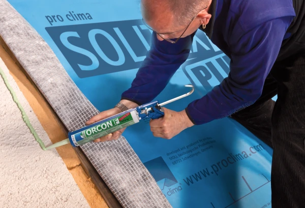 Orcon F being applied on an external wall underneath a sheet of Solitex Plus.