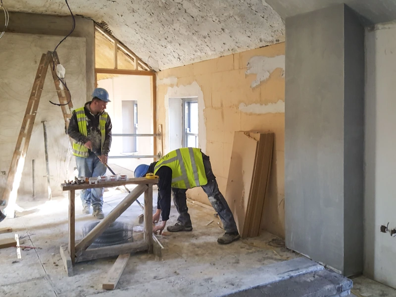 Two men applying Gutex Thermoroom to a visitor centre wall.