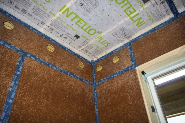 The corner junction of a wall fitted with Finsa airtight racking boards and showing core holes for blown-in insulation