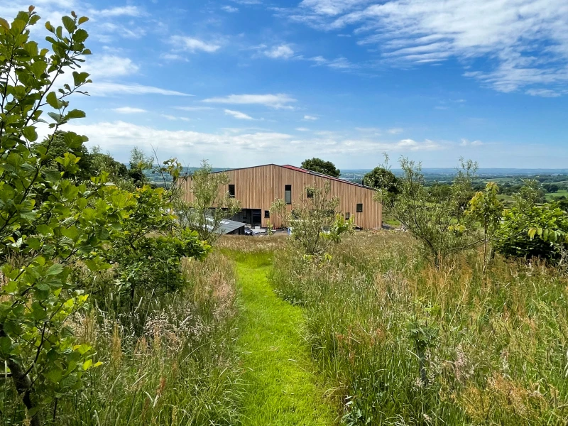 Knockboy barn passive house with trees and shrubs in foreground