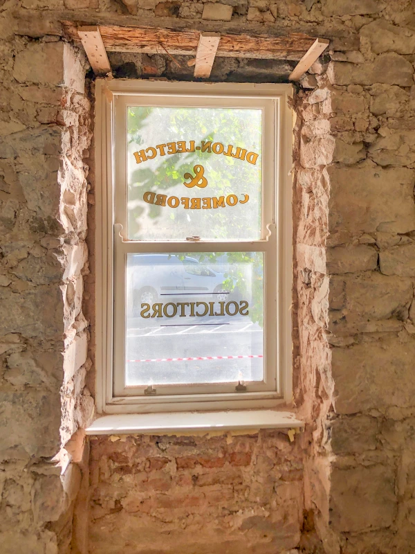 Exposed stone wall at window opening with original window glass from previous occupancy