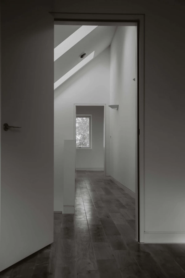 Internal view of a hallway with wooden flooring and and two open doors. 